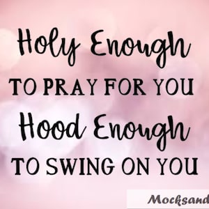 May include: A pink and white blurred background with a black text overlay that reads "Holy Enough To Pray For You Hood Enough To Swing On You". The text is in a cursive font. The text is centered on the image. The image also includes the text "MocksandMore" in the bottom right corner.