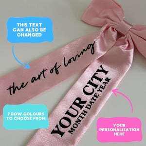 Pode incluir: Um laço de cetim rosa claro com o texto "the art of loving" e "YOUR CITY MONTH DATE YEAR" impresso em preto. A imagem também inclui o texto "THIS TEXT CAN ALSO BE CHANGED", "7 BOW COLOURS TO CHOOSE FROM", e "YOUR PERSONALISATION HERE".