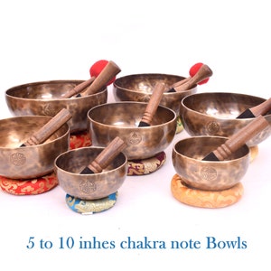 May include: Set of seven antique-looking singing bowls with wooden strikers. The bowls are various sizes, ranging from 5 to 10 inches in diameter. Each bowl has a unique design and is resting on a colorful cushion.  5 to 10 inches chakra note Bowls