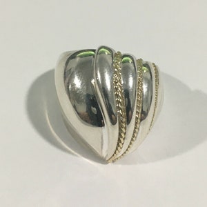 May include: A silver ring with a textured, curved design and three gold bands.