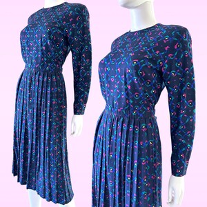 May include: A navy blue dress with a colorful geometric print. The dress has a pleated skirt and long sleeves.