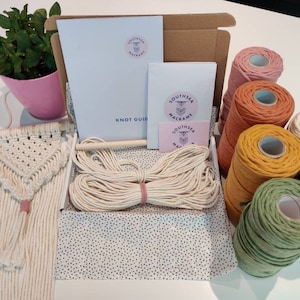 May include: A macrame kit containing a wooden dowel, white cord, and a knot guide. The kit also includes six spools of coloured cord in pink, orange, yellow, light blue, and green.