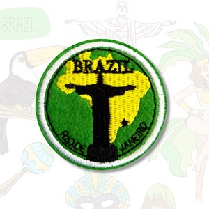 Puede incluir: Un parche bordado verde y amarillo con una silueta negra de la estatua de Cristo Redentor frente a un contorno del continente sudamericano. Las palabras "BRAZIL" y "RIO DE JANEIRO" están bordadas en blanco alrededor del borde del parche.