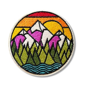 Peut inclure: Patch brodé représentant une scène de montagne colorée. Le patch présente un coucher de soleil avec des rayures orange, jaunes et rouges, une chaîne de montagnes rose avec des sommets enneigés blancs, des arbres verts et une rivière bleue.
