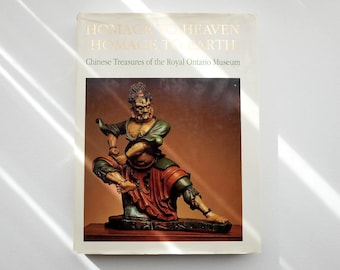 May include: A softcover book titled Homage to Heaven Homage to Earth Chinese Treasures of the Royal Ontario Museum. The cover features a photograph of a painted sculpture of a dynamic figure in green and red robes on a dark base.