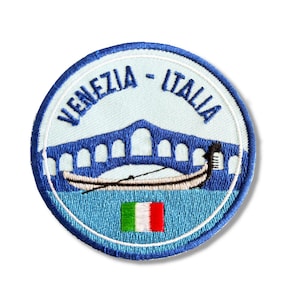 Może przedstawiać: Naszywka haftowana w kolorze niebieskim i białym z tekstem "Venezia - Italia" i przedstawieniem mostu i gondoli z włoską flagą.