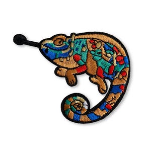 Peut inclure: Écusson brodé d'un caméléon coloré avec une queue enroulée. Le patch présente un motif détaillé avec des nuances de bleu, de vert, de rouge et d'or, souligné en noir. La langue du caméléon est tendue.