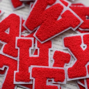 Peut inclure: Lettres en feutre rouge avec des contours blancs. Les lettres sont A, H, E, V et X.