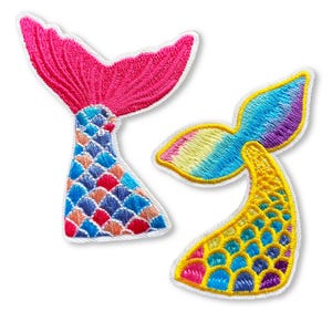 May include: Two embroidered iron-on patches featuring mermaid tails. One tail is pink and blue with a rainbow-coloured fin. The other tail is yellow and blue with a rainbow-coloured fin.