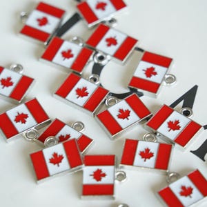 May include: A group of silver charms featuring the Canadian flag. Each charm is a small rectangular shape with a red background and a white maple leaf in the center.