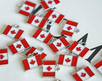 May include: A group of silver charms featuring the Canadian flag. Each charm is a small rectangular shape with a red background and a white maple leaf in the center.