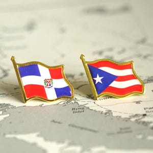 May include: Two flag pins, one of the Dominican Republic and one of Puerto Rico, with gold borders. The flags are red, white, and blue, set against a map background.