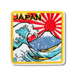 May include: Embroidered patch with a white background featuring a blue wave, a red and white rising sun, and a blue mountain with the word "JAPAN" in yellow letters.