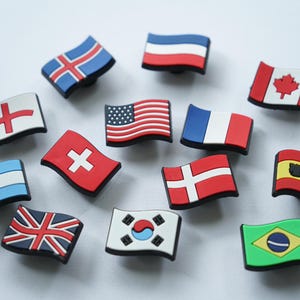 May include: A set of 12 small, colorful, rubber flag charms. The flags include: Iceland, England, Switzerland, Argentina, United Kingdom, South Korea, Brazil, France, Denmark, Spain, Canada, and the United States.