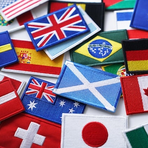 Puede incluir: Una colección de parches de tela bordados con banderas de diferentes países, incluyendo Estados Unidos, Reino Unido, Suecia, España, Escocia, Australia, Japón, Canadá, Alemania y la Unión Europea.