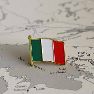Peut inclure: Une épingle dorée avec le drapeau italien sur une carte. Le drapeau est vert, blanc et rouge. La carte montre l'emplacement de "Parry Sound" et "Owen Sound".