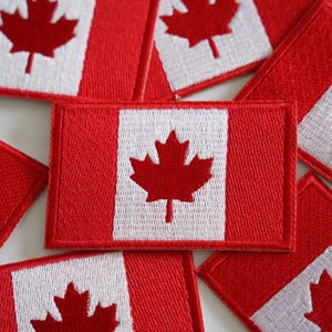 May include: Several red and white Canadian flag patches featuring a maple leaf design.