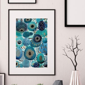 May include: Abstract art print featuring a blue and gold design with overlapping circles and geometric shapes. The print is framed in black and displayed on a white wall.