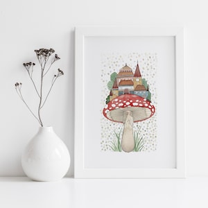 May include: A white framed print of a watercolor illustration of a red and white mushroom with a small town built on top. The mushroom is surrounded by green grass and a light blue sky with white dots.