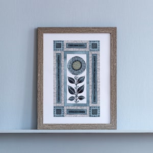 May include: A framed print of a stylized blue and gray flower with geometric patterns. The flower is surrounded by a border of geometric shapes.