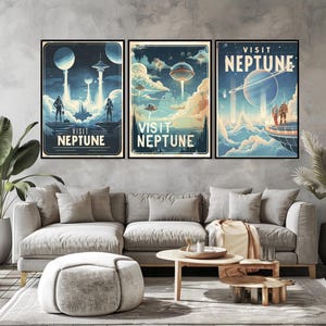 May include: Three framed art prints with a retro space travel theme. Each print features the words "Visit Neptune" with illustrations of futuristic spacecraft, planets, and figures in a blue and beige color palette. The prints are displayed above a gray sofa.