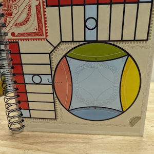 May include: A spiral bound notebook with a colorful design on the cover. The design features a circular pattern with red, yellow, blue, and green sections. The text "ENTER" is visible on the cover.