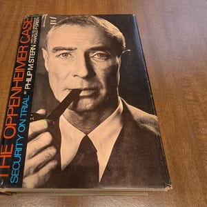 May include: A hardcover book titled "The Oppenheimer Case: Security on Trial" by Philip M. Stern and Harold P. Green. The cover features a black and white portrait of a man holding a pipe. The book's title is in blue and orange text.