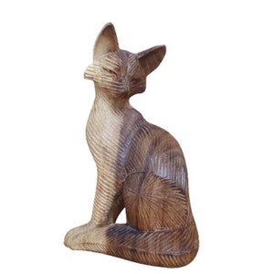 May include: A wooden cat figurine with a brown and white striped pattern. The cat is sitting with its head turned to the side and its tail curled around its body.