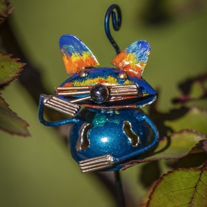 May include: A blue metal mouse figurine with orange, yellow and blue paint accents. The mouse is sitting on a green leaf with a curled tail.