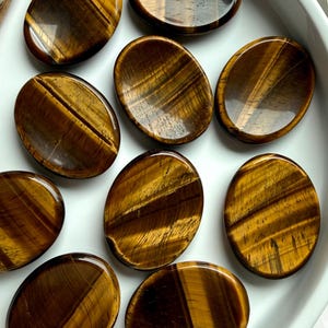 top view of tiger’s eye thumb stones in bowl with rich golden brown tones, worry stones for confidence grounding and focus