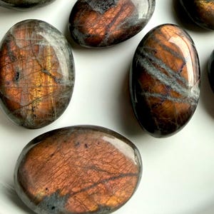 Peach Sunset Labradorite palm stones with glowing orange and peach flash on white tray