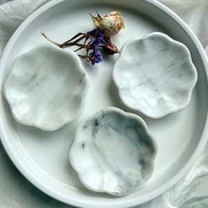 Set of three white marble daisy bowls with natural gray veining, styled with dried flowers on white tray