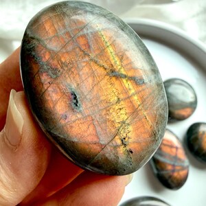 Close-up of Peach Sunset Labradorite palm stone showing orange, pink, and golden labradorescence