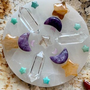 Crystal grid on round selenite plate with clear quartz double terminated quartz points, golden healer stars, lepidolite moons, amazonite stars, and golden rutile star in center