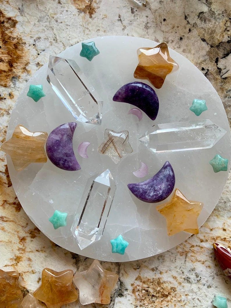 Crystal grid on round selenite plate with clear quartz double terminated quartz points, golden healer stars, lepidolite moons, amazonite stars, and golden rutile star in center