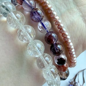 stacked crystal bracelets featuring Super Seven quartz, Rainbow Crackle Quartz, and pink pearl beads for feminine energy, emotional healing, intuition, and spiritual balance