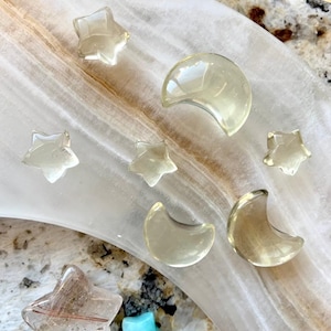 Lemon Citrine moon and star carvings displayed with Clear Quartz points and crystals on a crescent moon dish