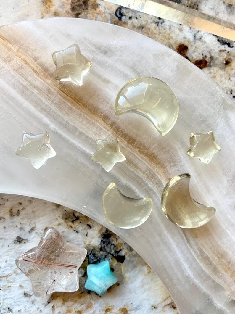 Lemon Citrine moon and star carvings displayed with Clear Quartz points and crystals on a crescent moon dish
