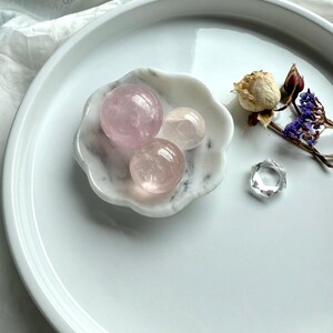 White marble daisy bowl styled as a sphere holder with three mini rose quartz spheres