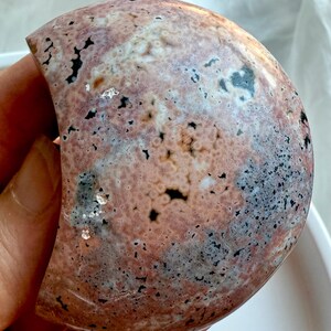 Ocean Jasper crescent moon crystal displaying soft pink, cream, and black orbicular patterns for calming energy