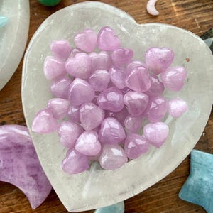 Clear Quartz heart bowl filled with Mini Pink Kunzite hearts, surrounded by other crystals — high-vibe crystal arrangement for love & heart chakra healing.