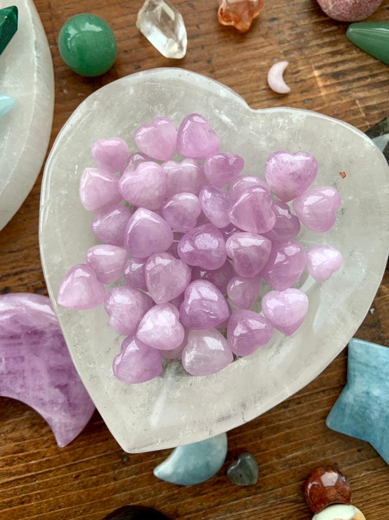 Clear Quartz heart bowl filled with Mini Pink Kunzite hearts, surrounded by other crystals — high-vibe crystal arrangement for love & heart chakra healing.
