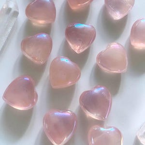 Array of glowing mini angel aura rose quartz hearts on a white background — radiant pink crystals for love, emotional healing & heart chakra energy