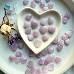 Mini Kunzite Hearts displayed in a heart dish with dried flowers and clear quartz – pink crystal hearts for love, compassion and gentle healing energy