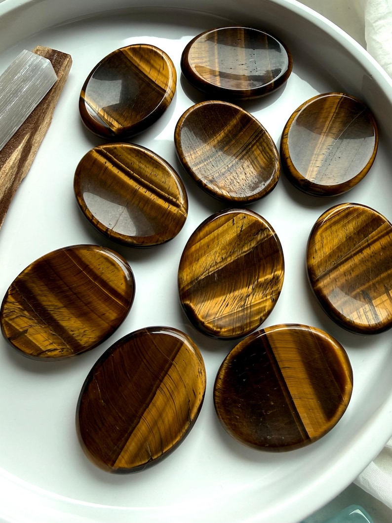 group of tiger’s eye worry stones scattered on marble surface, polished crystals for grounding stability and energy protection