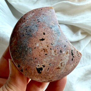 back view of ocean jasper moon showing soft pink, peach, and grey orbicular patterns, natural gemstone carving for grounding and emotional harmony