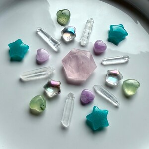 Mini crystal carvings arranged in a healing crystal grid with Prehnite hearts featuring Epidote inclusions, Kunzite, Aura Quartz, Amazonite, Rose Quartz hexagon, and clear Quartz points for chakra balance, love, and clarity.