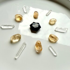 Crystal grid for protection with faceted Black Obsidian hexagon in center, surrounded by citrine tumbles and clear quartz points radiating outward