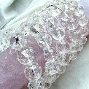 Rainbow Clear Quartz bracelet displayed on pink rose quartz with luminous transparent crystal beads