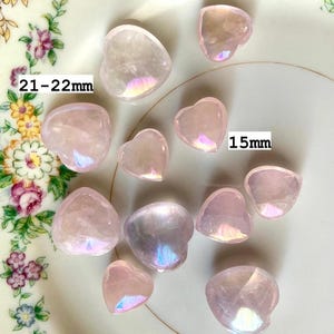 Translucent aura rose quartz hearts on a floral plate with sizes marked — dreamy pink crystals for emotional healing & heart-centered energy work